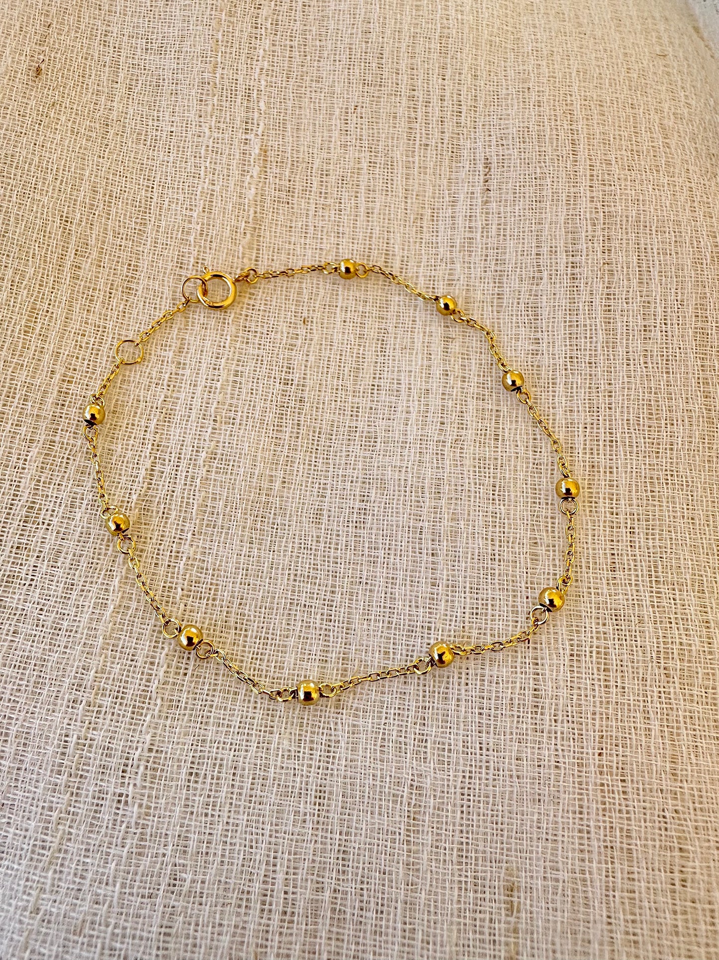 Gold Ball Bracelet featuring gold beads strung seamlessly on a delicate chain.
This Simple Gold bracelet is perfect for a minimalistic stand alone look or for stacking with other bracelets.