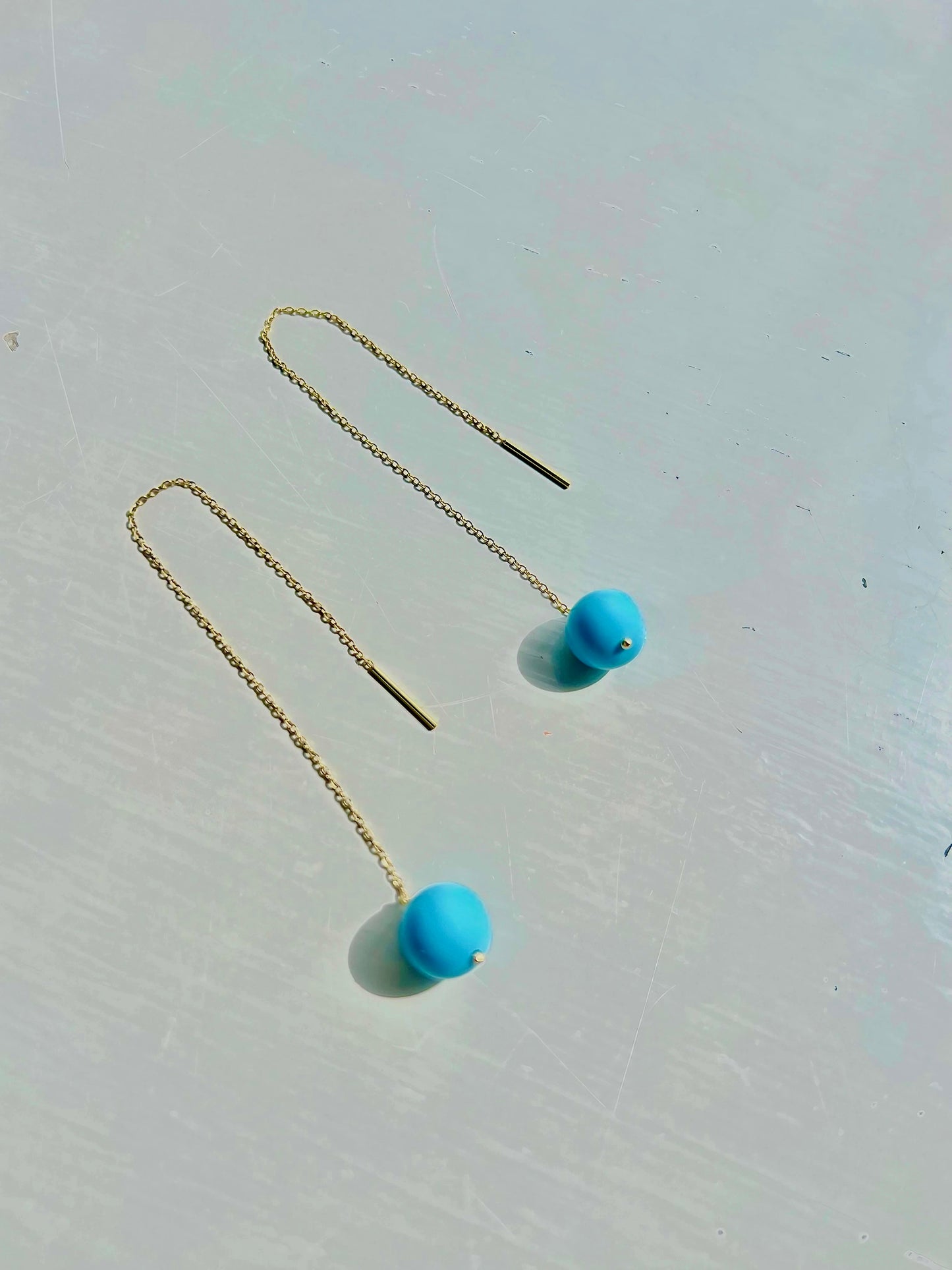 Delicate Gold Threader Earrings featuring a minimalist design that effortlessly blends modern chic with timeless charm. Adorned with a round turquoise bead at its end.