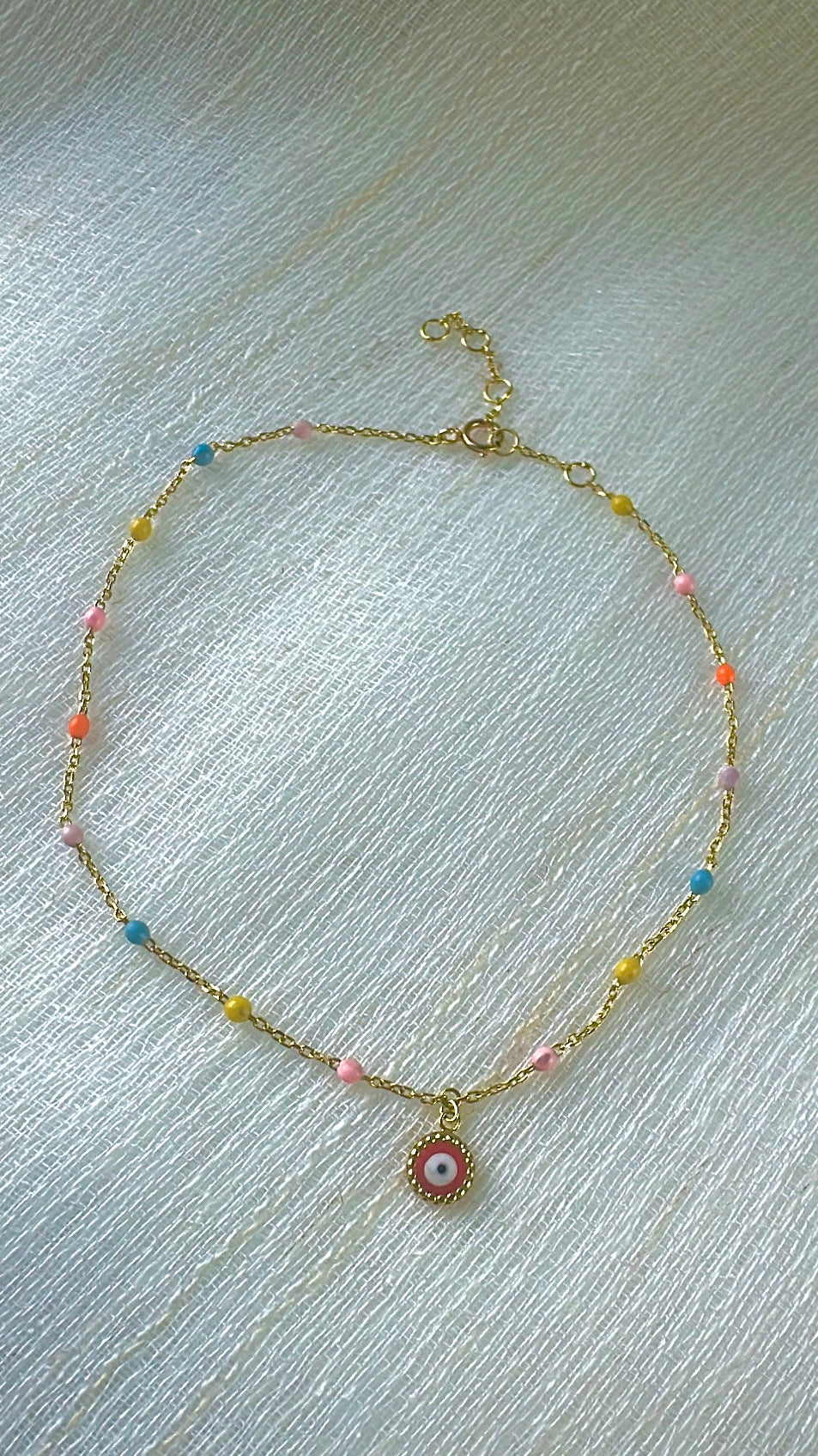 Evil Eye Anklet handcrafted in 18 karat gold, featuring colorful enamel points and a dangling Evil Eye Charm customizable enamel finish. Adjustable Length | Ella creations Jewelry
