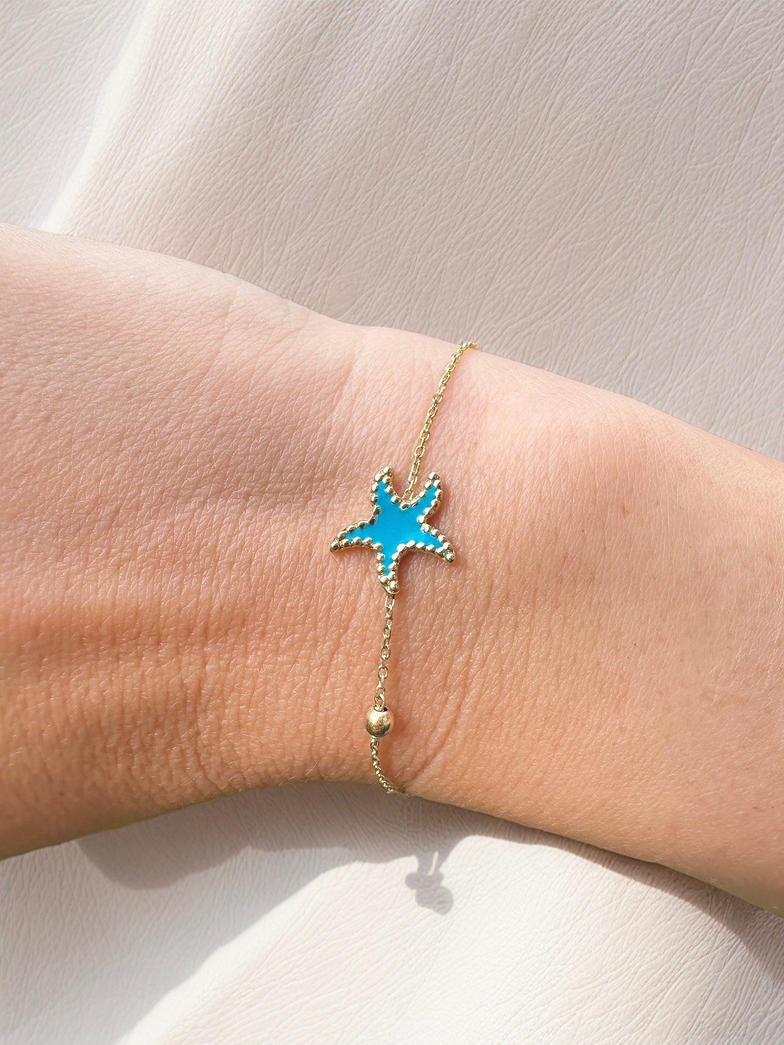 Exquisite Starfish Bracelet features a starfish charm at its center, available in Bright Turquoise and baby Pink finishes. Handcrafted in 18k gold and you can opt whether to have the charm only or an addition to a gold or enamel bead. | Ella Creations Jewelry