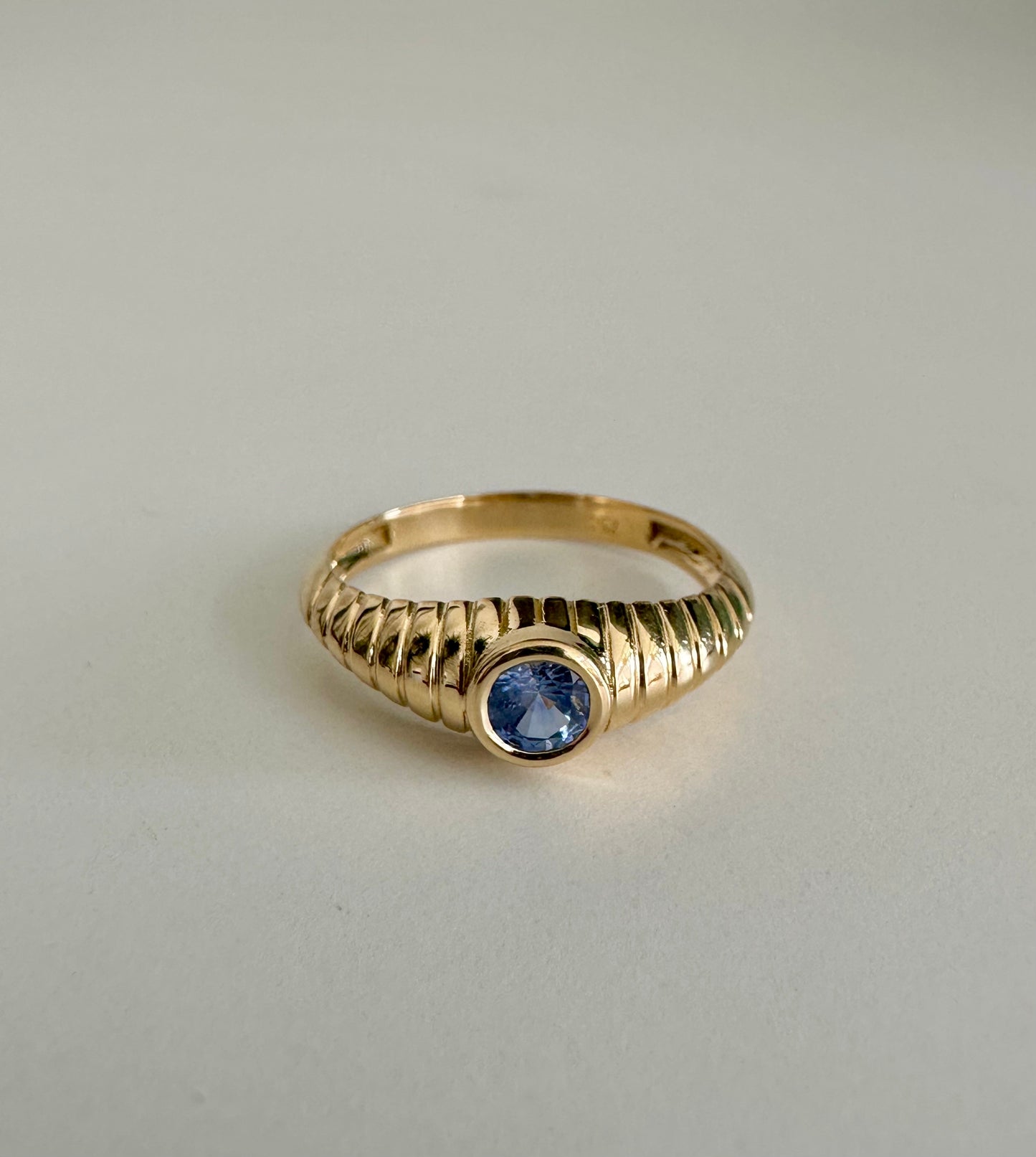 Gold Mina Sapphire Ring features a unique design that combines modern elements with a vintage-inspired aesthetic. It's a custom made ring showcasing a 4.3 mm bezel set Sapphire at its center | Ella Creations Jewelry