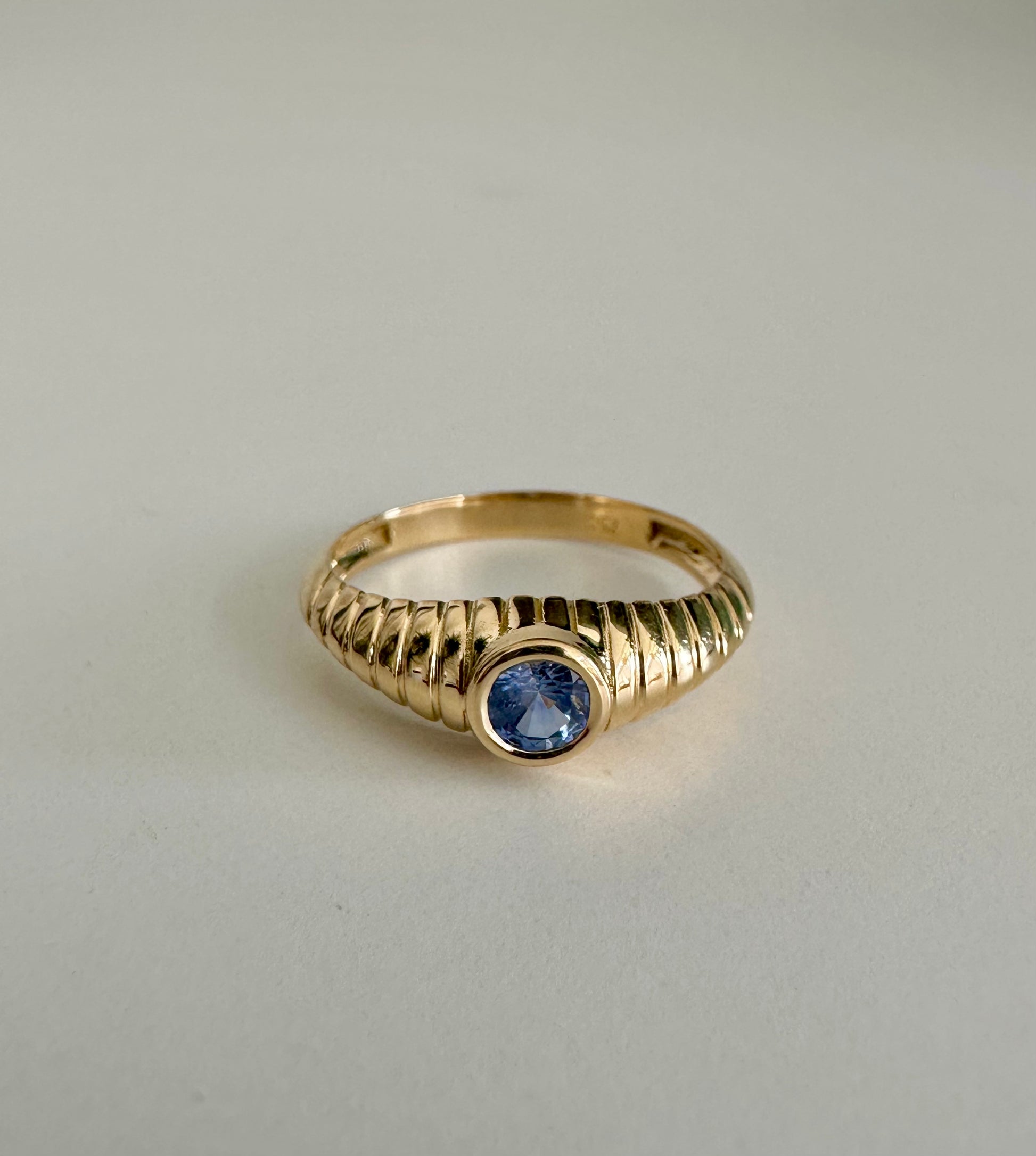 Gold Mina Sapphire Ring features a unique design that combines modern elements with a vintage-inspired aesthetic. It's a custom made ring showcasing a 4.3 mm bezel set Sapphire at its center | Ella Creations Jewelry