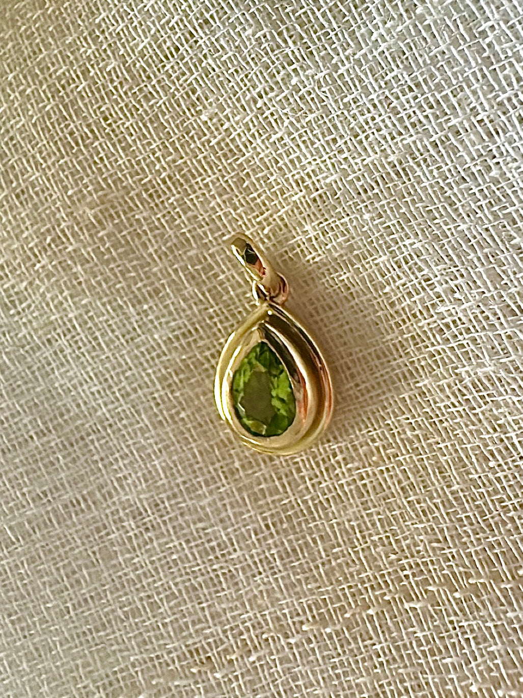 Peridot pendant, set into a custom, two-tiered 18k gold bezel that matches the stone's pear shape. The pendant has a solid gold back with an opening behind the stone to allow the light to best reflect the stone shade and sparkle.