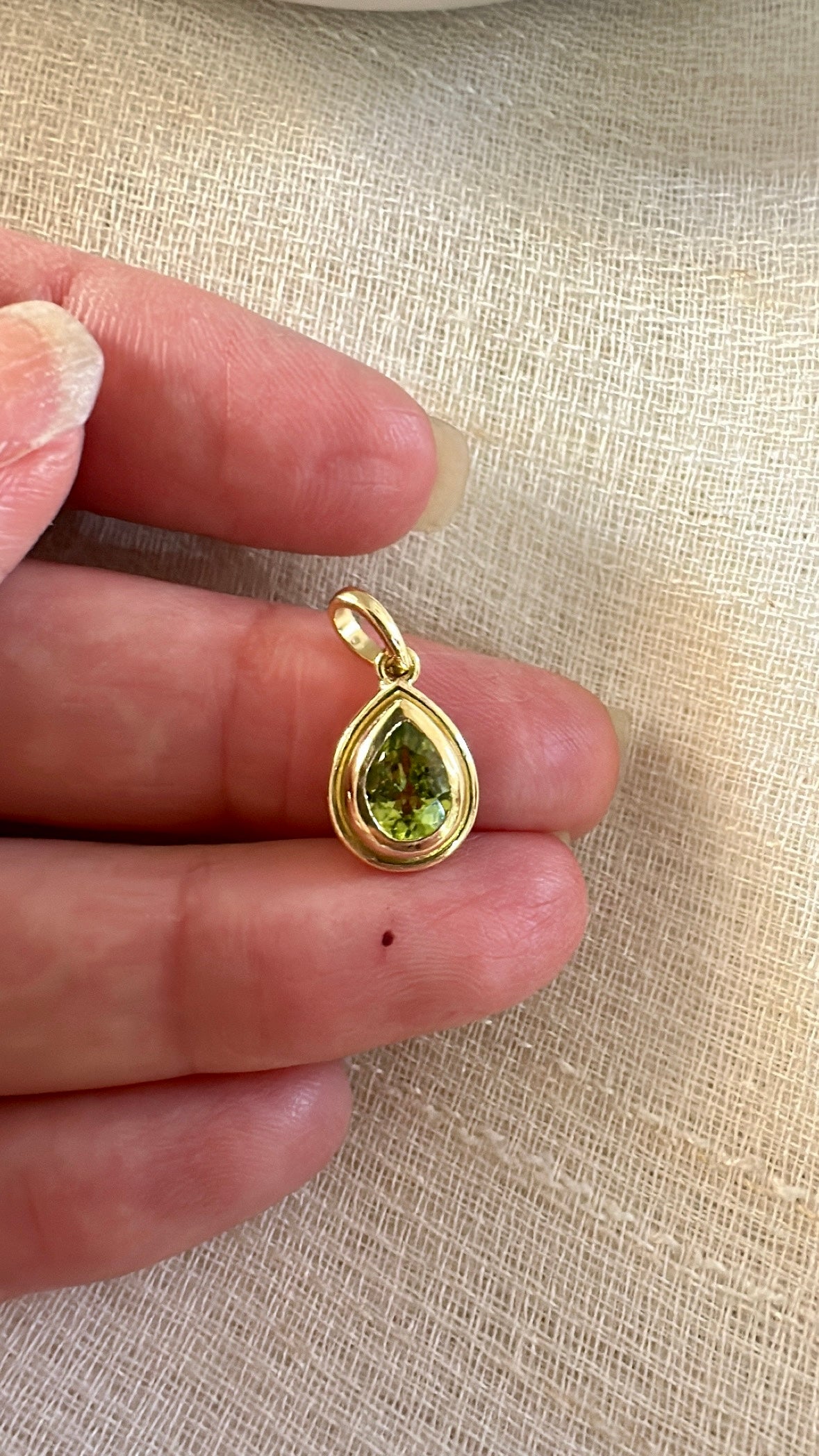 Peridot pendant, set into a custom, two-tiered 18k gold bezel that matches the stone's pear shape. The pendant has a solid gold back with an opening behind the stone to allow the light to best reflect the stone shade and sparkle.