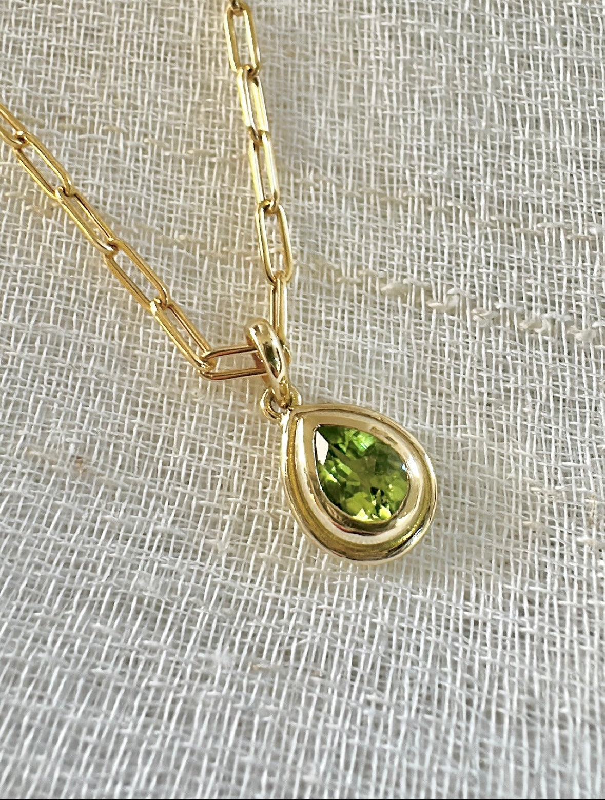 Peridot pendant, set into a custom, two-tiered 18k gold bezel that matches the stone's pear shape. The pendant has a solid gold back with an opening behind the stone to allow the light to best reflect the stone shade and sparkle | Ella Creations Jewelry