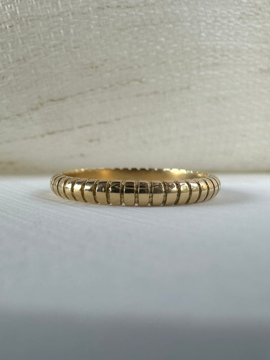 Thin 18k gold ribbed wedding band on finger
