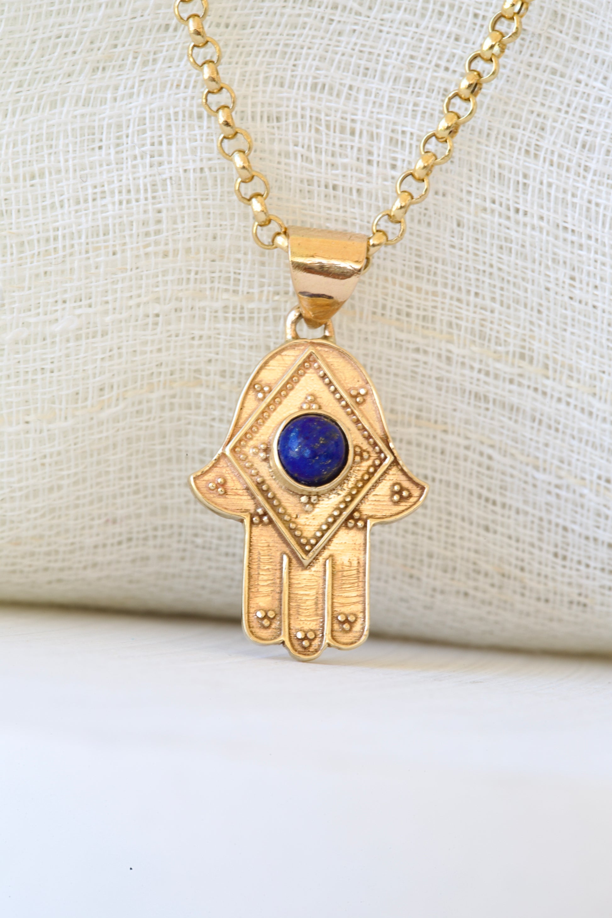 Stylish Gold Hamza Pendant adorned with a Lapis LazuliBlue Stone at the center. Customizable in 14K or 18K