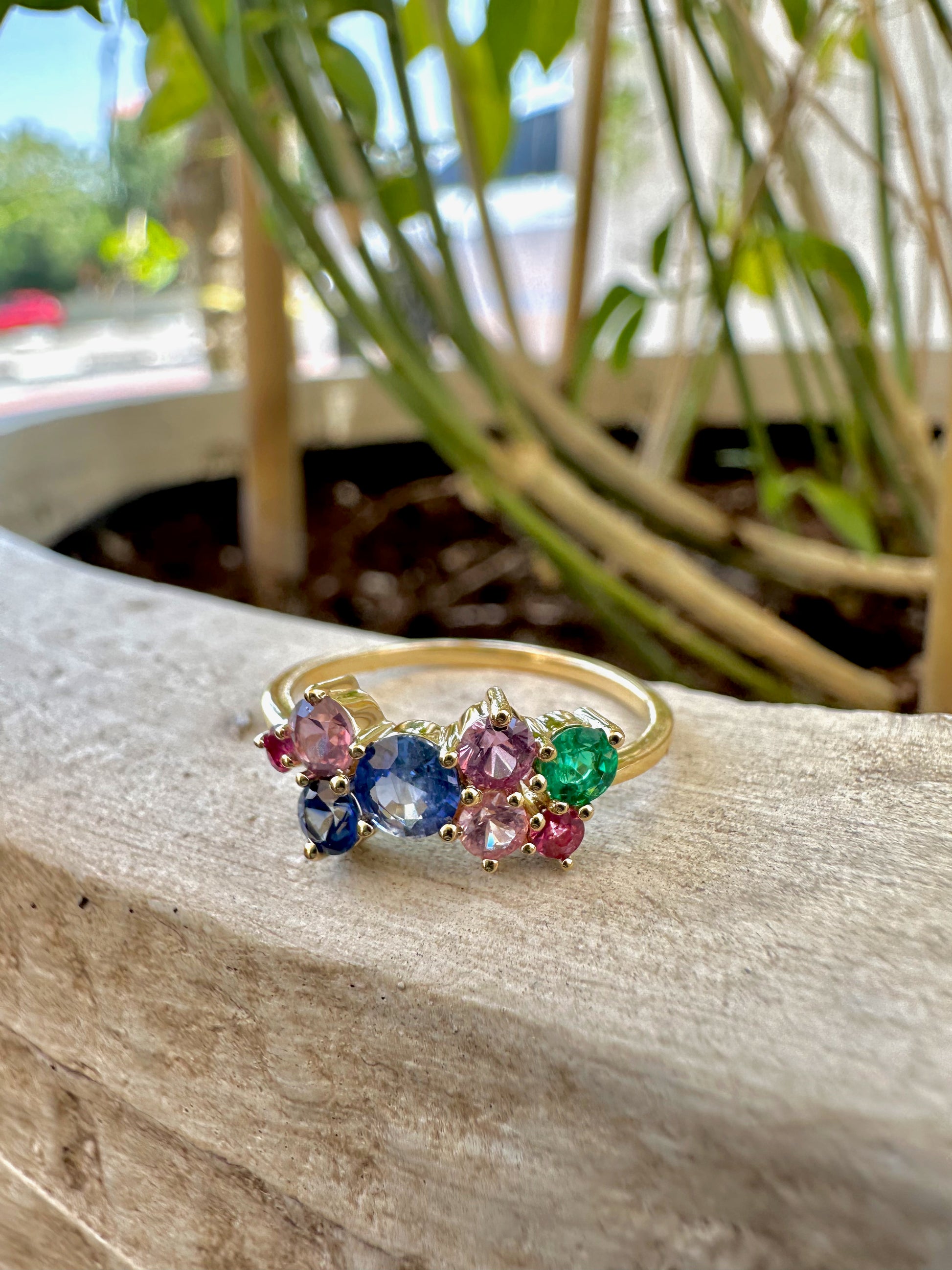 Rainbow Sapphire Ring features a stunning natural multicolor sapphires in a cluster ring design. The various Sapphires, of different sizes and colors, along with one natural emerald, are placed randomly to form this beautiful rainbow ring.
This ring is set in a timeless classic 18 karat gold, featuring a dainty band. | Ella Creations Jewelry 
