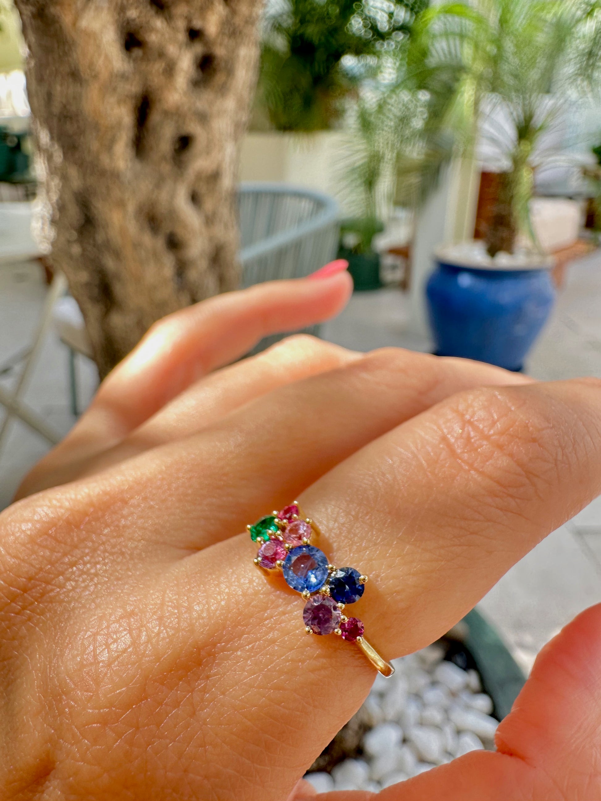 Rainbow Sapphire Ring features a stunning natural multicolor sapphires in a cluster ring design. The various Sapphires, of different sizes and colors, along with one natural emerald, are placed randomly to form this beautiful rainbow ring.
This ring is set in a timeless classic 18 karat gold, featuring a dainty band. | Ella Creations Jewelry 